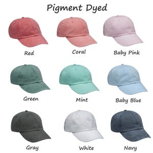 May include: Nine pigment dyed baseball caps in various colors, including red, coral, baby pink, green, mint, baby blue, gray, white, and navy.