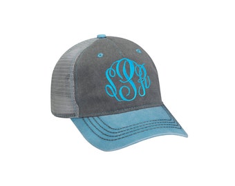 May include: A gray and teal baseball cap with a mesh back. The cap features a teal monogram in a script font on the front. The text "Teal - Font #29" is at the bottom of the image.