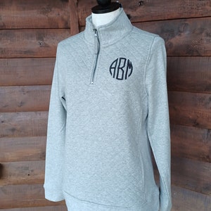 May include: A gray quilted quarter-zip pullover with a black monogram "ABM" on the chest.