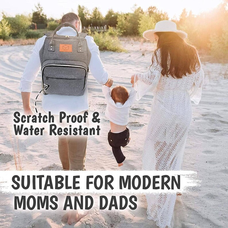 K&ouml;nnte beinhalten: Eine graue Wickeltasche mit einer Rei&szlig;verschlusstasche und dem Text "Scratch Proof & Water Resistant" auf der Vorderseite. Die Tasche wird von einer Person auf dem R&uuml;cken getragen. Der Text "Suitable for Modern Moms and Dads" steht am unteren Rand des Bildes.