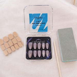Peut inclure: Un ensemble de dix faux ongles en amande couleur mauve avec un motif d'étoile dans un boîtier en plastique transparent marqué COSMAE. Comprend un sachet de préparation et lingette Mylee 2-en-1, des adhésifs beiges, un bâtonnet et une lime.
