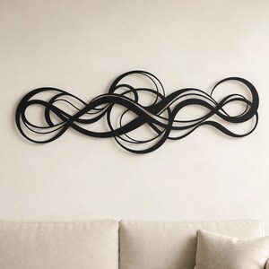 May include: A black metal wall art piece featuring a series of interconnected, flowing, and overlapping curved lines that create an abstract, continuous, and elongated horizontal design with multiple circular loops and wave-like patterns throughout.