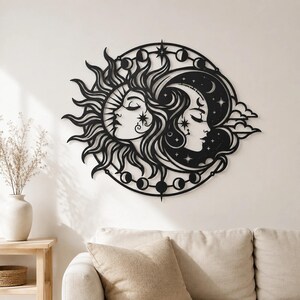 May include: A circular black metal wall art piece featuring a stylized sun and moon face design. The sun rays extend outward, while the moon is surrounded by clouds and stars. A border displays various moon phases in a continuous circular pattern.