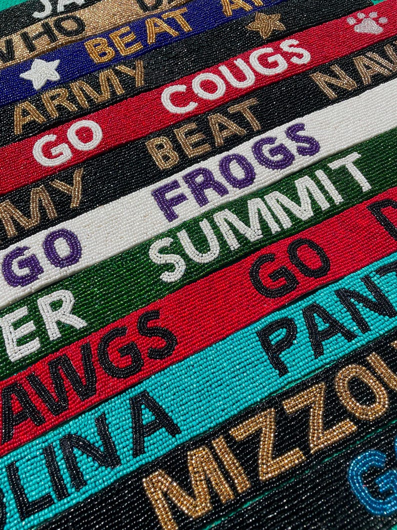 May include: A collection of rectangular beaded straps featuring various team-themed text and symbols. The straps are rendered in diverse colors including red, black, white, green, blue, and gold, with embroidered lettering such as COUGS, FROGS, SUMMIT, DAWGS, PANTHERS, and MIZZOU.