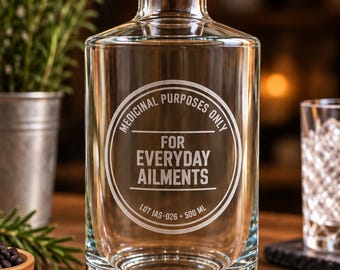 May include: A clear glass bottle with a wooden cork stopper. The front features white etched text reading MEDICINAL PURPOSES ONLY FOR EVERYDAY AILMENTS LOT IAS-026 500 ML. The bottle has a cylindrical body with a thick base and a short neck.