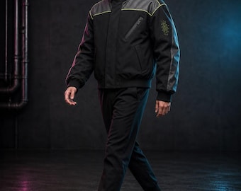 May include: A black hooded jacket with a high collar, front zipper, and neon yellow piping accents. The jacket features textured shoulder panels, a zippered chest pocket, and a small graphic print on the left sleeve, paired with matching black joggers.