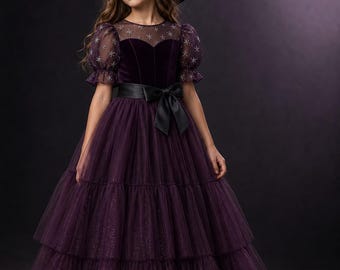 May include: A floor-length purple dress with a velvet bodice, puff sleeves, and a tiered tulle skirt featuring star patterns. The dress includes a black satin waist sash with a bow and is paired with a matching purple velvet witch hat with a star.