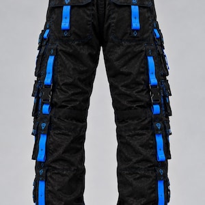 May include: Black cargo pants featuring a subtle tonal pattern, multiple side pockets, and bright blue nylon straps with black plastic buckles. The waistband includes a black buckle belt, and the leg cuffs have adjustable blue drawstrings.