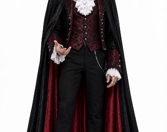 May include: A long black cape with a deep red lining, worn over a dark red patterned vest and a black jacket with ornate silver buttons. The outfit includes a white ruffled cravat with a red gemstone brooch, black trousers, and black dress shoes.