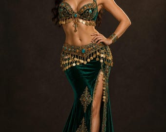 May include: A dark green velvet two-piece outfit featuring a bra top and a floor-length skirt with a high side slit. The set is embellished with gold embroidery, dangling gold coins, and turquoise-colored oval stones throughout.