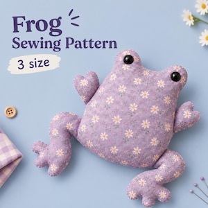 May include: A stuffed frog toy made from light purple fabric with a white daisy floral pattern. The frog has two black plastic eyes and heart-shaped hands. Text on the image reads Frog Sewing Pattern 3 size.