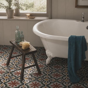 Puede incluir: Una bañera blanca con patas de garra, grifo cromado y una toalla azul verdoso colgada en el borde. Junto a la bañera hay un pequeño taburete de madera marrón oscura con tres botellas de vidrio y dos esponjas naturales sobre baldosas.