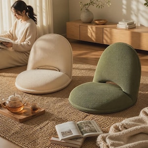 May include: Two floor chairs with rounded backs and seats, upholstered in a textured corduroy fabric. One chair is cream-colored, and the other is sage green. Both chairs feature a low-profile design without legs, resting directly on the floor.