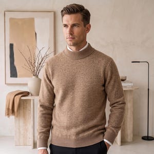 Könnte beinhalten: Ein beigefarbener Pullover mit Stehkragen und strukturierter Strickoptik, ausgestattet mit langen Ärmeln und gerippten Bündchen, getragen über einem weißen Hemd mit Kragen. Der Pullover hat eine neutrale Farbe und eine körpernahe Passform.