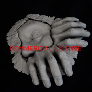 May include: A grey sculpture depicting a single eye peering through a jagged, torn opening, flanked by two hands with fingers gripping the textured edges. The text COMMERCIAL LICENSE is printed in red across the center of the sculpture.