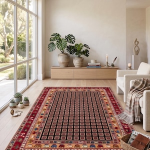 Könnte beinhalten: Ein rechteckiger Teppich mit einem zentralen schwarzen Feld, das ein Gitter aus kleinen Quadraten aufweist, umgeben von mehreren dekorativen Bordüren in Rot, Beige und Creme. Die Bordüren zeigen wiederkehrende Muster aus Tieren und geometrischen Formen.