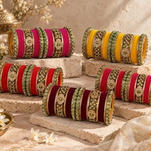 Peut inclure: Cinq ensembles de bracelets en magenta, jaune, rouge, rose et bordeaux. Chaque ensemble comprend des bracelets unis alternés avec des bandes métalliques ornées d'accents circulaires verts et de motifs floraux centraux avec des pierres claires.