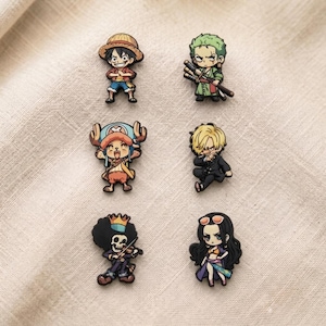 May include: A set of six colourful character shoe charms featuring anime-style figures. The collection includes a boy in a straw hat, a green-haired swordsman, a reindeer-like creature, a blonde man in a suit, a skeleton musician, and a woman with long hair.