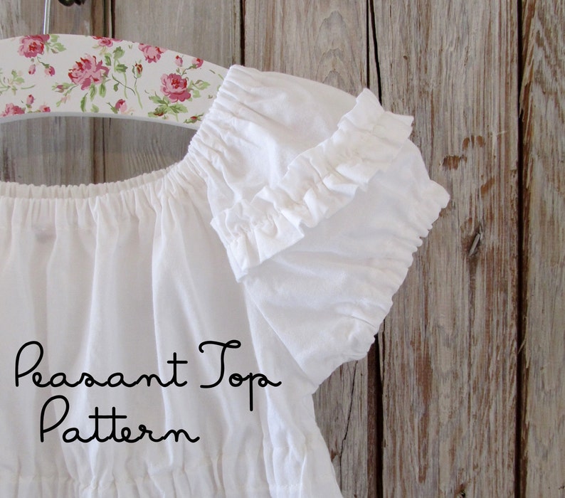 May include: White peasant top with ruffled sleeves hanging on a floral patterned hanger. The text "Peasant Top Pattern" is written below the top.