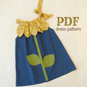 Peut inclure: Une robe bleue sans manches avec un motif de tournesol jaune sur l'encolure et des feuilles vertes sur le devant. La robe a un ruban vert au centre. Le texte "PDF dress pattern" est en brun sur fond blanc.