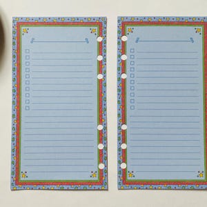May include: Two rectangular light blue planner pages with six binder holes on the inner edges. The pages feature a border with colourful stars and a red line, horizontal lines for writing, and a column of empty checkboxes for task tracking.