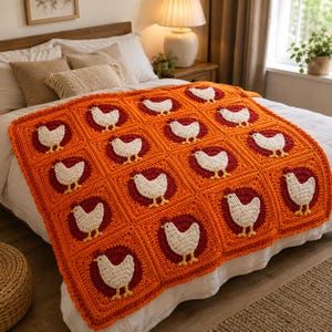 May include: A handmade crochet blanket featuring a repeating pattern of white chickens with red combs on dark red circular backgrounds, all framed within bright orange square borders. The blanket has a scalloped edge and a textured yarn construction.