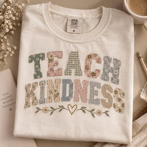 T-Shirt mit dem Aufdruck „Lehre Freundlichkeit“ | florales Patchwork-Muster mit Buchstaben, Herz und Zweigen