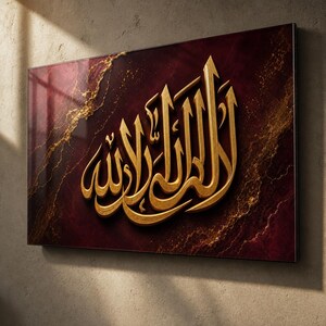 Puede incluir: Una pieza de arte mural rectangular que presenta caligrafía árabe en relieve de color oro metálico centrada sobre un fondo burdeos intenso. El fondo muestra una textura marmolada con vetas doradas en espiral.