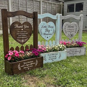 May include: Three wooden planter boxes with attached heart-shaped signs and picket fence accents. Each planter features floral arrangements and printed text including Thank You, Little Things Big Memories, and Home is where our story begins.