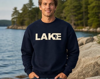 Puede incluir: Una sudadera azul marino de cuello redondo con la palabra LAKE impresa en letras mayúsculas grandes de color crema en el pecho, con una pequeña silueta gráfica de un pino integrada en la letra K.