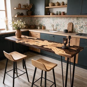 Può includere: Un tavolo rettangolare da isola cucina con piano in legno a bordo naturale e inserti in resina scura, sostenuto da quattro sottili gambe in metallo nero. Due sgabelli da bar in legno coordinati con gambe in metallo nero sono posizionati davanti.