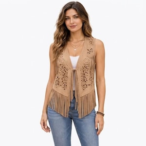 Könnte beinhalten: Eine ärmellose Weste in Beige mit filigranen, lasergeschnittenen Blumenmustern im Brust- und Schulterbereich, verziert mit langen Fransen am Saum und an der Vorderseite, getragen über einem schlichten weißen Oberteil und blauen Jeans.