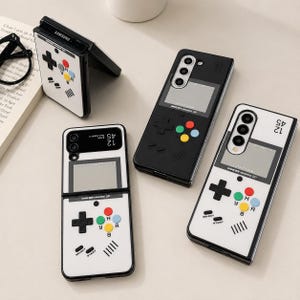 May include: Four smartphone cases featuring a retro handheld gaming console design. Three cases are white and one is black, each displaying a directional pad, A, B, Y, and X buttons, and the text Game Boy Advance SP. The cases have cutouts for camera lenses.