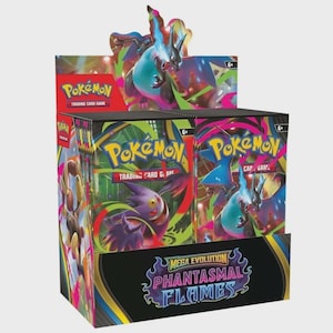 Può includere: Una scatola espositrice di bustine del Gioco di Carte Collezionabili Pokémon intitolata Mega Evolution Phantasmal Flames. La scatola presenta illustrazioni colorate di Charizard e Gengar, con il logo Pokémon e l'età 6+ chiaramente visibili.