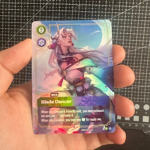Può includere: Una carta collezionabile rettangolare con l'illustrazione di un personaggio dai lunghi capelli bianchi e un abito viola e turchese. La carta riporta il testo Irelia, Blade Dancer e istruzioni di gioco. Codice SFD-195/220 presente.