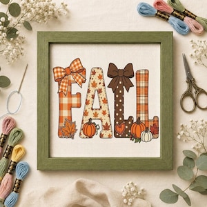 Può includere: Un ricamo a punto croce incorniciato che raffigura la parola FALL in lettere decorative. La F ha un motivo a quadri arancione con un fiocco, la A ha foglie d'acero e una zucca, la L ha pois marroni con un fiocco e la L è a quadri.