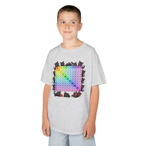 May include: A light grey short-sleeved t-shirt featuring a colourful multiplication table grid from 1 to 10. The grid is surrounded by illustrations of small black cats playing with red yarn balls, set against a white background on the shirt.