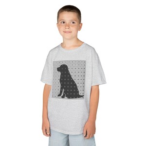 May include: A light grey short-sleeve t-shirt featuring a centred graphic of a black dog silhouette overlaid on a grid containing the numbers 1 through 100 in black text. The shirt has a crew neckline and a standard fit, made of a heathered fabric.