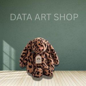 Puede incluir: Un peluche con forma de conejo con un estampado de leopardo en tonos marrón y negro. El conejo tiene orejas largas y caídas, una pequeña nariz rosa y una etiqueta beige alrededor del cuello con el texto JELLYCAT LONDON impreso.