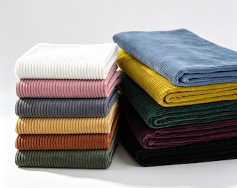 May include: Two stacks of folded corduroy fabric in various colors. The left stack includes white, pink, gray, yellow, rust, and olive green. The right stack features blue, mustard yellow, dark green, deep purple, and black fabric pieces.