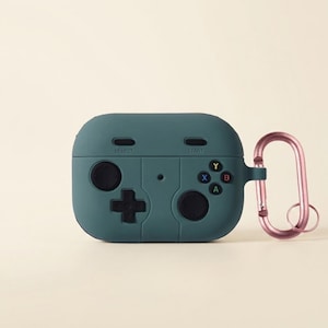 May include: A dark teal silicone protective case for wireless earbuds, designed to resemble a retro game controller. It features a directional pad, two joysticks, four colored action buttons labeled A, B, X, Y, and Select and Start text.