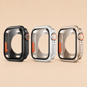 Pode incluir: Três capas protetoras para smartwatches, dispostas em fila. As capas são preta, prateada e dourada, cada uma com uma cobertura de tela transparente, um botão lateral e um distinto detalhe laranja na coroa giratória no lado direito.