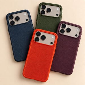 May include: Four smartphone cases with a textured fabric finish, each featuring a triple-lens camera cutout and a light-coloured camera module frame. The cases are available in navy blue, olive green, bright orange, and deep burgundy colour options.