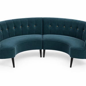 Op de afbeelding: Een gebogen bank bekleed met diepblauwe fluwelen stof. De rugleuning is voorzien van verticale kanaalstiksels met kleine, lichtgekleurde knopen in het midden van elk gedeelte. Het meubelstuk rust op vier taps toelopende, donkergekleurde houten poten.
