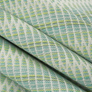 May include: Close-up of a woven fabric with a green and white geometric pattern. The fabric has a textured surface and a subtle sheen.