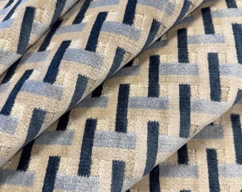 May include: A woven fabric featuring a geometric pattern of interlocking rectangles in shades of navy blue, light blue, and beige. The material has a textured, plush surface with a repeating grid-like design that creates depth and visual interest.