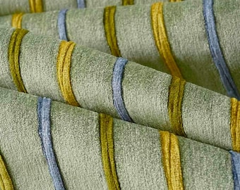 May include: A sage green fabric featuring a textured surface with vertical stripes in alternating shades of mustard yellow and slate blue. The material has a soft, plush appearance with raised, corded lines running across the folded textile.