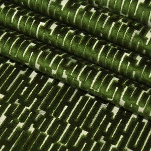 May include: Green velvet fabric with a white geometric pattern. The fabric has a raised texture and a luxurious feel.
