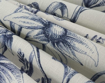 May include: A piece of off-white fabric featuring a repeating dark blue floral pattern. The textile has a visible woven texture and is draped in soft folds, showcasing the detailed botanical illustrations of flowers and stems across the surface.
