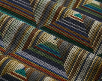 May include: A woven fabric featuring a geometric pattern of repeating stepped pyramids. The textile displays a textured grid surface with a color palette of dark gray, olive green, mustard yellow, teal, and rust orange stripes.